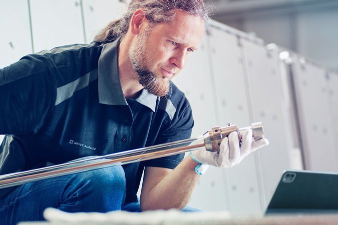 Photo of a man looking at a tablet and performing maintenance work